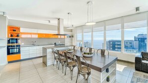 A modern kitchen with a central island, large windows, and a view of the cityscape.