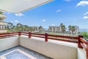 A balcony with a view of a beach and cityscape, including palm trees and high-rise buildings.