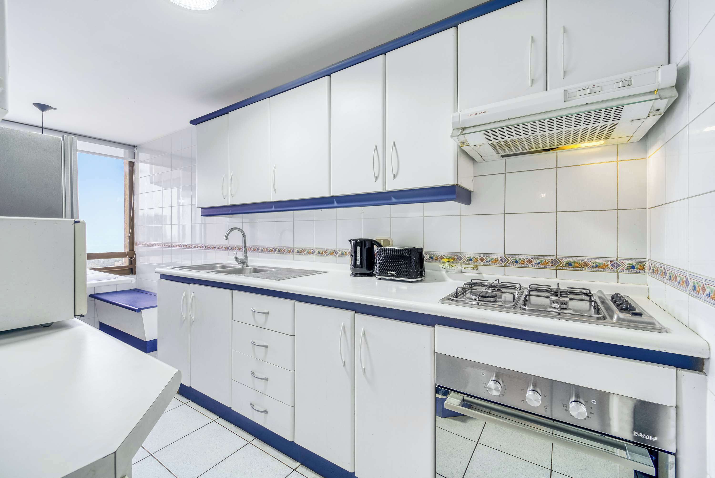 A modern kitchen with white cabinets, a gas stove, and a built-in oven.