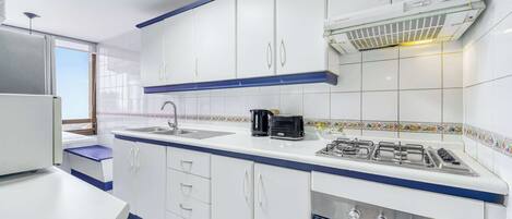 A modern kitchen with white cabinets, a gas stove, and a built-in oven.