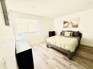A bedroom with a bed, a window, a desk, and a speaker. - Perfect 4-bedroom house with AC & High ceilings for the Summer (Los Angeles)