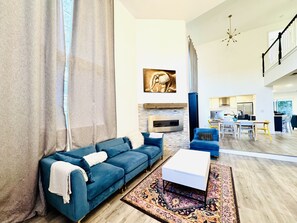 A modern living room with a blue sofa, a white coffee table, and a patterned rug. - Perfect 4-bedroom house with AC & High ceilings for the Summer (Los Angeles)