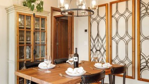 A dining area with a wooden table, black leather chairs, a chandelier, and a cabinet with glass doors.