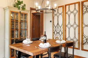A dining area with a wooden table, black leather chairs, a chandelier, and a cabinet with glass doors.
