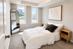 Une chambre avec un grand lit, un miroir, deux tables de chevet et une vue sur l’extérieur.