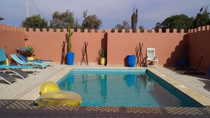 Una piscina con sillones de descanso, flotadores y plantas en macetas.