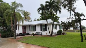 Einbungalow mit roter Tür, weißem Anstrich und einer Veranda mit einer Bank.