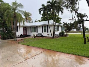 Einbungalow mit roter Tür, weißem Anstrich und einer Veranda mit einer Bank.