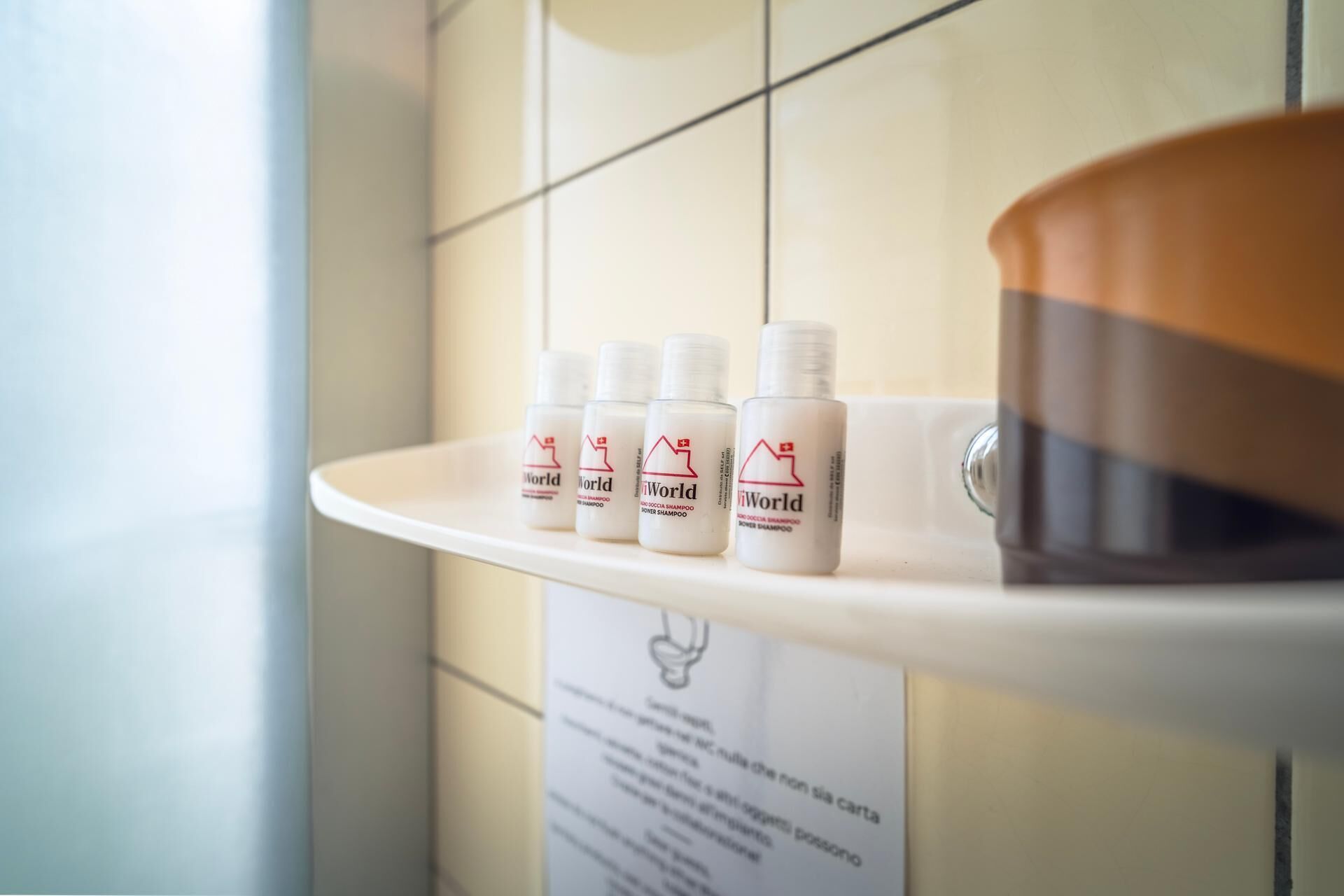 A bathroom shelf with four bottles of shampoo and a bowl.