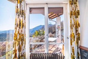 A room with a view of a mountainous landscape through a large window with curtains. - Panorama Stay near Lugano (Bigorio)