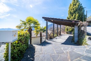 A stone pathway leading to a wooden pergola with 'CASA - Panorama Stay near Lugano (Bigorio)