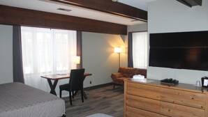 Une chambre d’hôtel équipée d’un lit, d’un bureau, d’une chaise, d’un canapé, d’une commode et d’un téléviseur.
