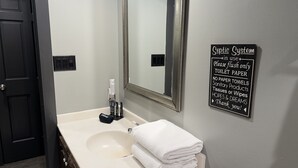 Une salle de bain équipée d’un lavabo, d’un miroir et d’un panneau indiquant que le système d’assainissement est en service.