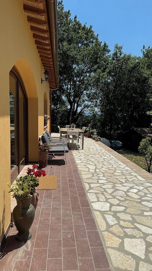A patio with outdoor furniture, a stone pathway, and a view of trees.