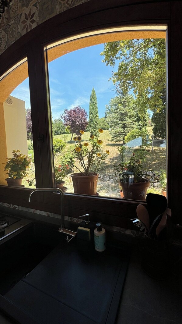 A kitchen with a window overlooking a garden.