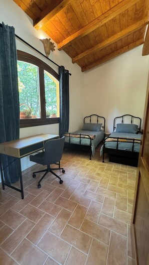 Quarto com duas camas, uma escrivaninha e uma cadeira.