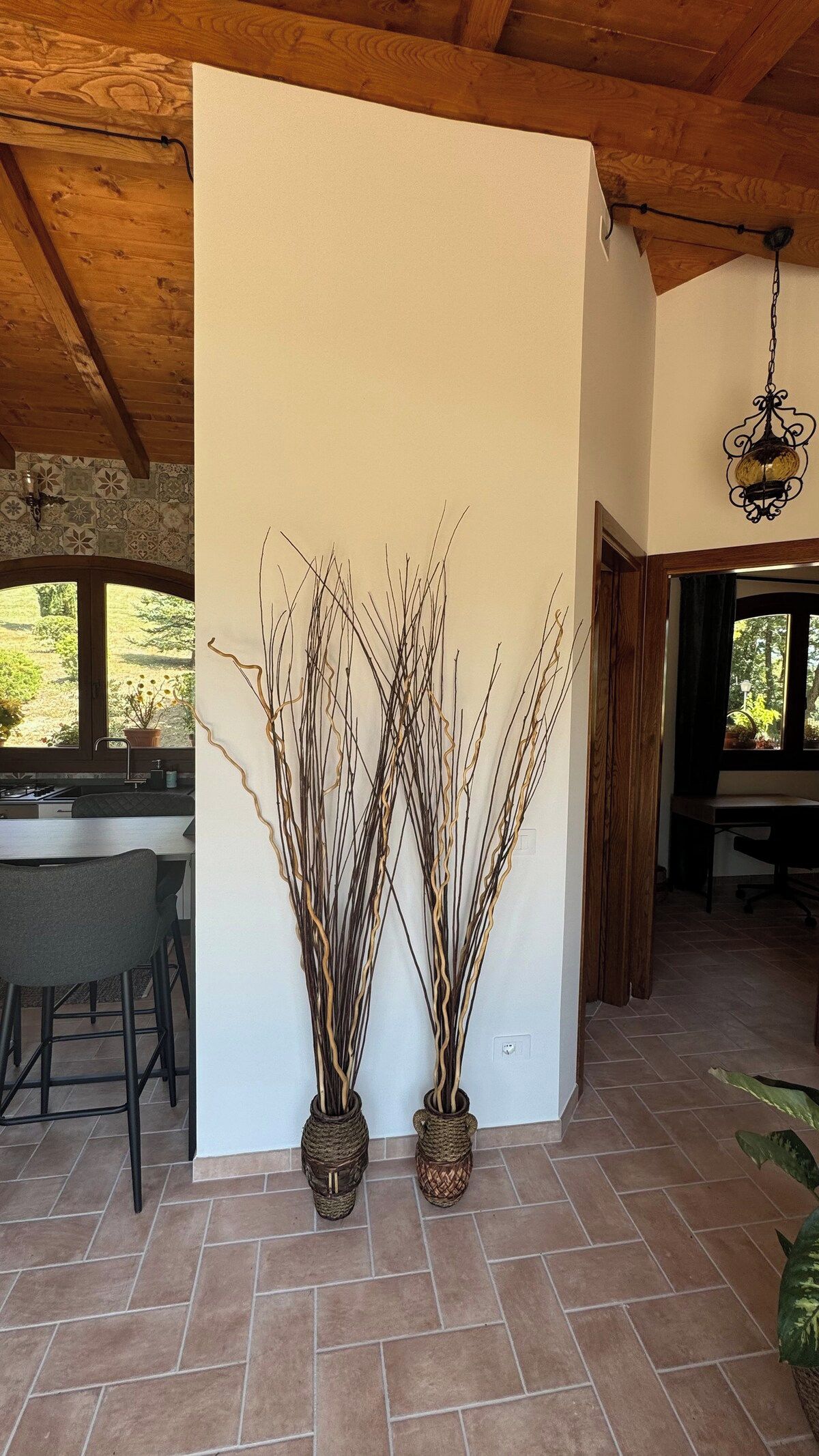 A room with a kitchen area, a dining table, and two tall decorative vases.