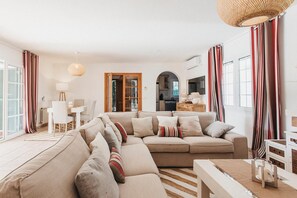 Ein Wohnzimmer mit einer Couch, einem Esstisch und einer Küche im Hintergrund.