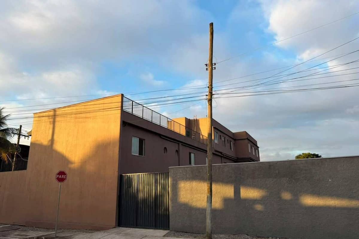 Un edificio con entrada protegida por una reja, una señal de parada y un poste de electricidad.