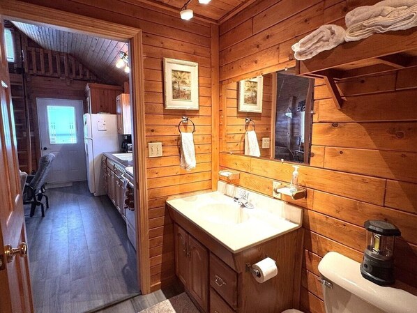 A wooden cabin bathroom with a sink, toilet, and a mirror.