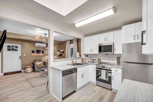 A modern kitchen with white cabinets, stainless steel appliances, and a visible dishwasher.