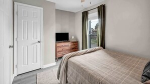 Quarto com cama, penteadeira, televisão e porta.
