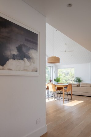 Ein modernes Interieur mit Essbereich, großem Fenster und hoher Decke.