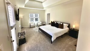 Un dormitorio con cama, ventilador de techo, ventana y una silla.