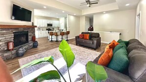 Un salón amplio con chimenea, sofás, televisor y ventiladores de techo.
