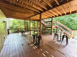 A wooden deck with outdoor seating, a staircase, and a view of greenery. - Atlanta Home: 2-Tier Deck & Wooded Views (Lithia Springs)