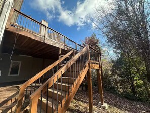 A wooden staircase leading to a balcony with a metal railing, surrounded by trees and a clear sky. - Atlanta Home: 2-Tier Deck & Wooded Views (Lithia Springs)