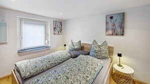 Camera da letto con due letti, una finestra con tende, una lampada sul comodino e decorazioni alle pareti.