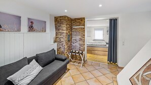 Un interno moderno con un divano grigio, una parete decorata in mattoni e un pavimento in legno.