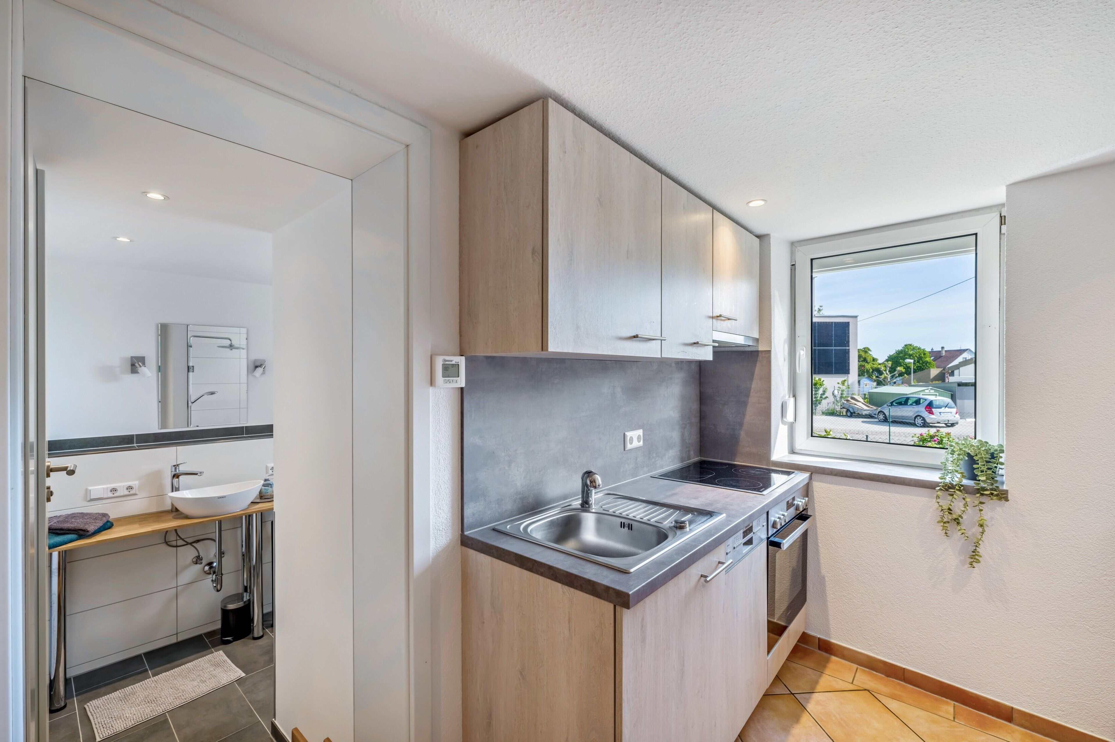 Une cuisine moderne équipée d’un évier, d’une cuisinière et d’une fenêtre donnant sur la rue.