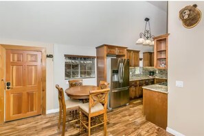 Eine Küche mit Holzausstattung, einem Edelstahlkühlschrank und einem Essbereich mit einem Holztisch und Stühlen.