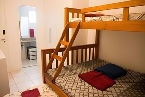 Un lit superposé avec une échelle en bois, un matelas à motifs et deux oreillers.