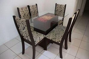 Une table à manger avec un plateau en verre, entourée de quatre chaises dont les revêtements sont ornés de motifs.