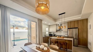 Une cuisine moderne avec des meubles en bois, un îlot central et un coin repas comprenant une table et des chaises.