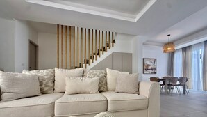 Un salon moderne avec un canapé, un escalier et un coin repas.