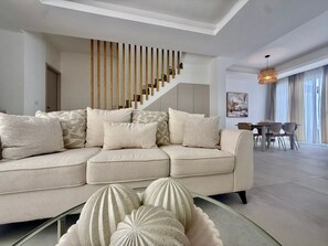 En moderne stue med sofa, sofabord i glas og dekorative vaser.