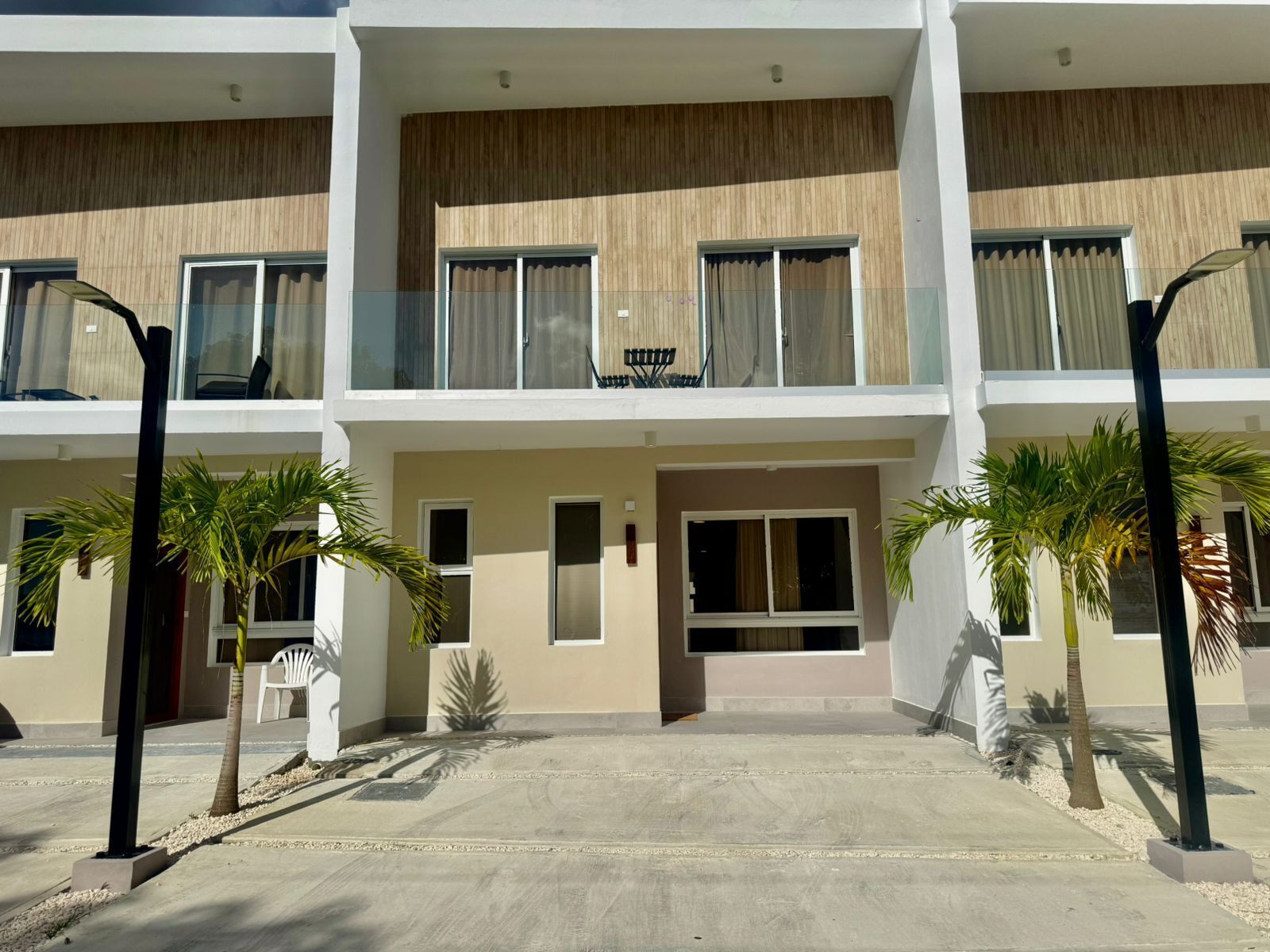 Un hôtel moderne à plusieurs étages, doté de balcons, de grandes fenêtres et de palmiers.