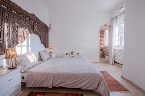 Ein Schlafzimmer mit einem großen Bett, einem Nachttisch, einer Lampe und einem dekorativen Kopfteil.