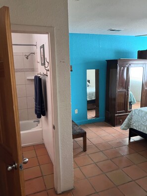 A bathroom with a bathtub, a shower, and a towel rack. - North Valley Charmer (Albuquerque)