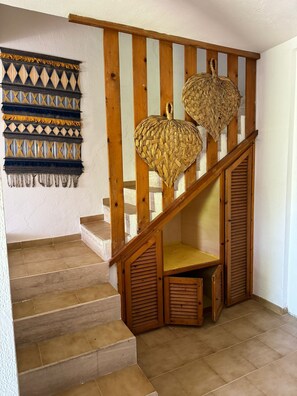 Eine Holztreppe mit einer Korbschmuck-Dekoration und einem gemusterten Wandbehang.