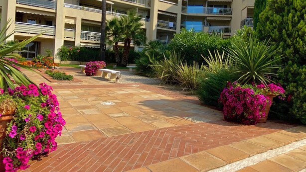 A multi-story building with balconies, a paved courtyard, and various plants. - Antibes - Studio for 2 people - Parking - Swimming pool - Air conditioning (Antibes)