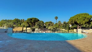 A swimming pool with a stone deck, surrounded by trees and a clear blue sky. - Antibes - Studio for 2 people - Parking - Swimming pool - Air conditioning (Antibes)