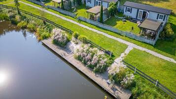 A residential area with a dock extending into a body of water, surrounded by lush greenery and a row of houses.