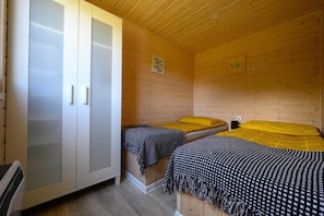 Una habitación de cabaña de madera con dos camas, un armario y un cartel en la pared.