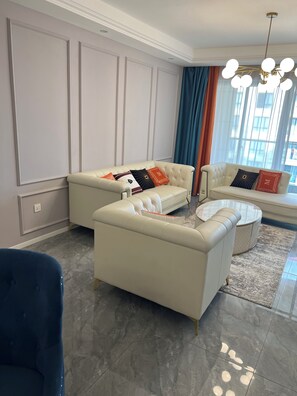A modern living room with two sofas, a coffee table, and a blue chair. - Cozy 2-bedroom bungalow with AC in charming Nairobi (Nairobi)