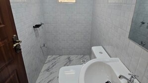 Ein Badezimmer mit weißen Fliesen, einem Marmorboden, einer Toilette, einem Waschbecken und einem Fenster.